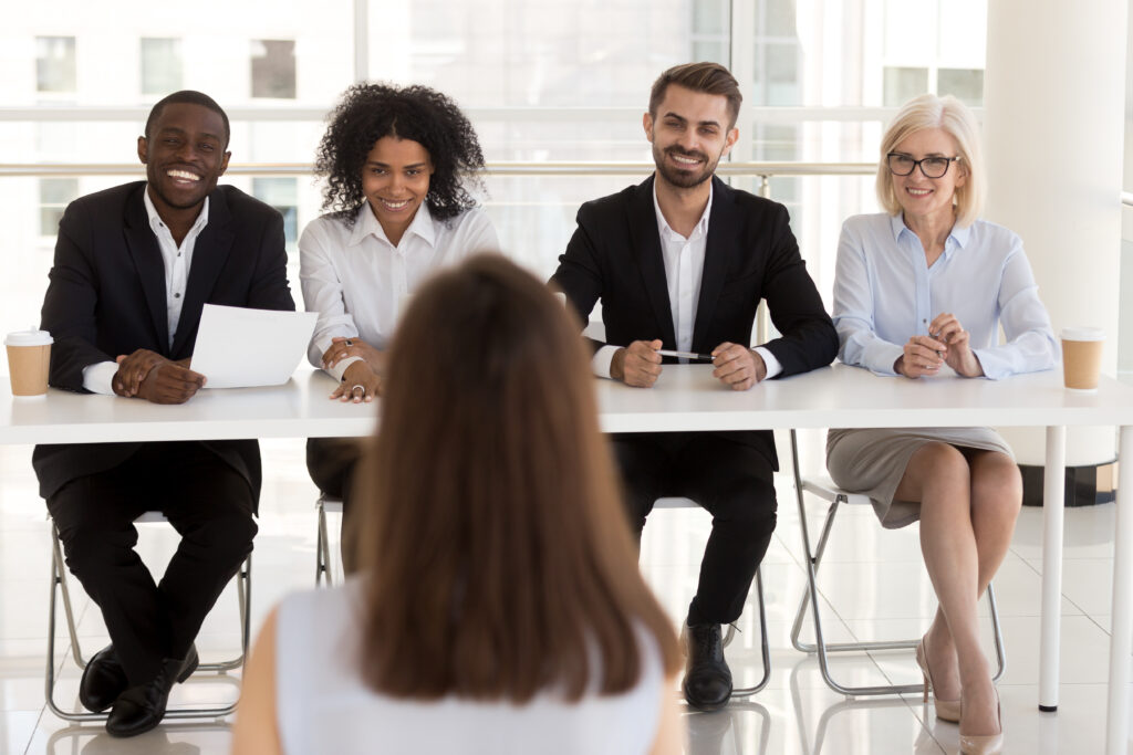 A diverse management team interviews a candidate to help implement the change management vision.