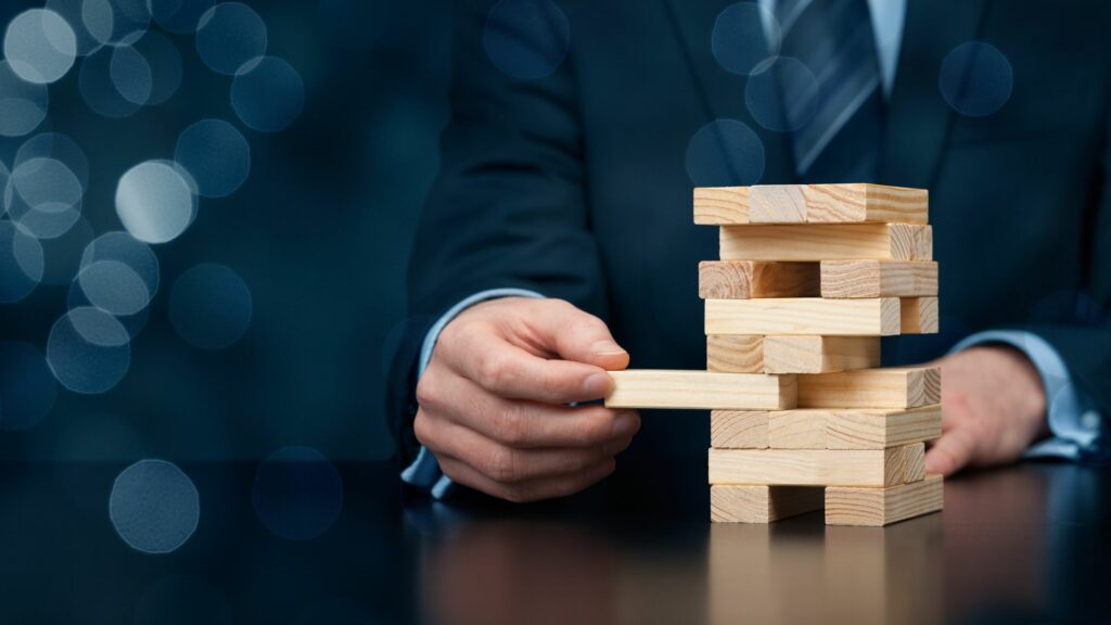 A businessman successfully removes a wooden block from a Jenga tower without it collapsing.