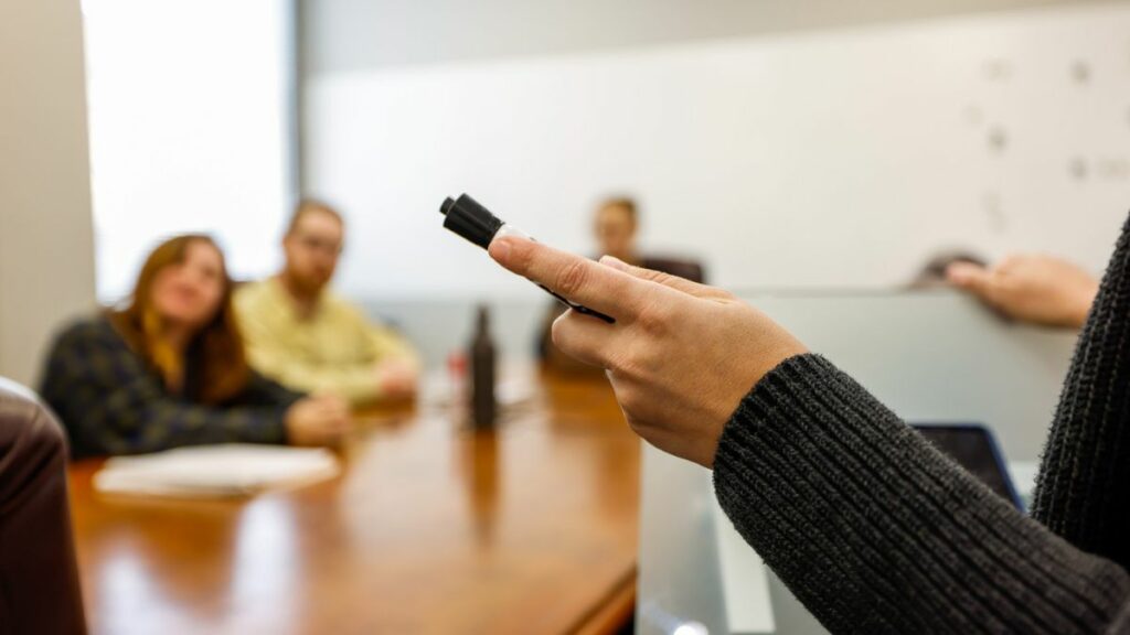 Instructor holds sharpie while teaching a small class of employees receiving strategic training.
