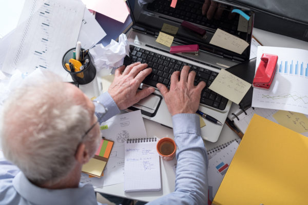 Top view of man working at a cluttered desk.