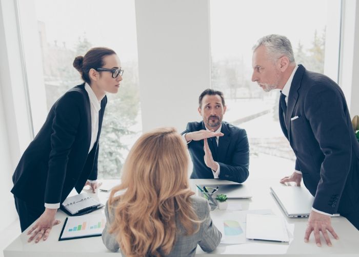 Employees arguing while boss calls time out to resolve conflict.