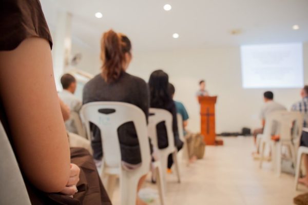 Church leader speaking in front of members, keeping them engaged as a way to increase church attendance.