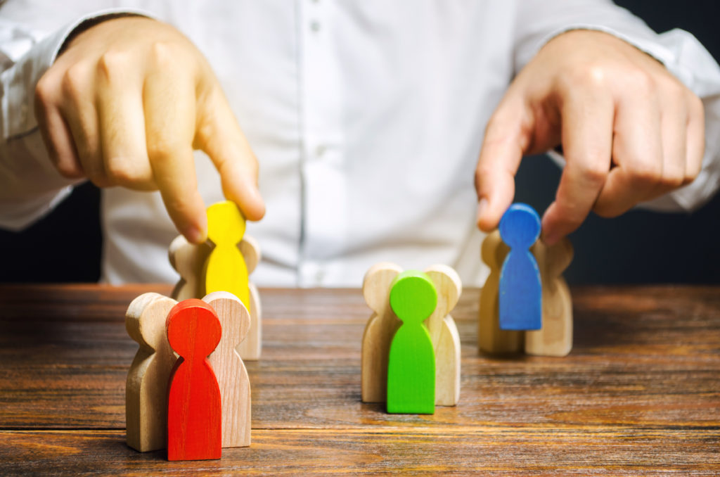  man moving groups of multicolored wooden people representing target audience