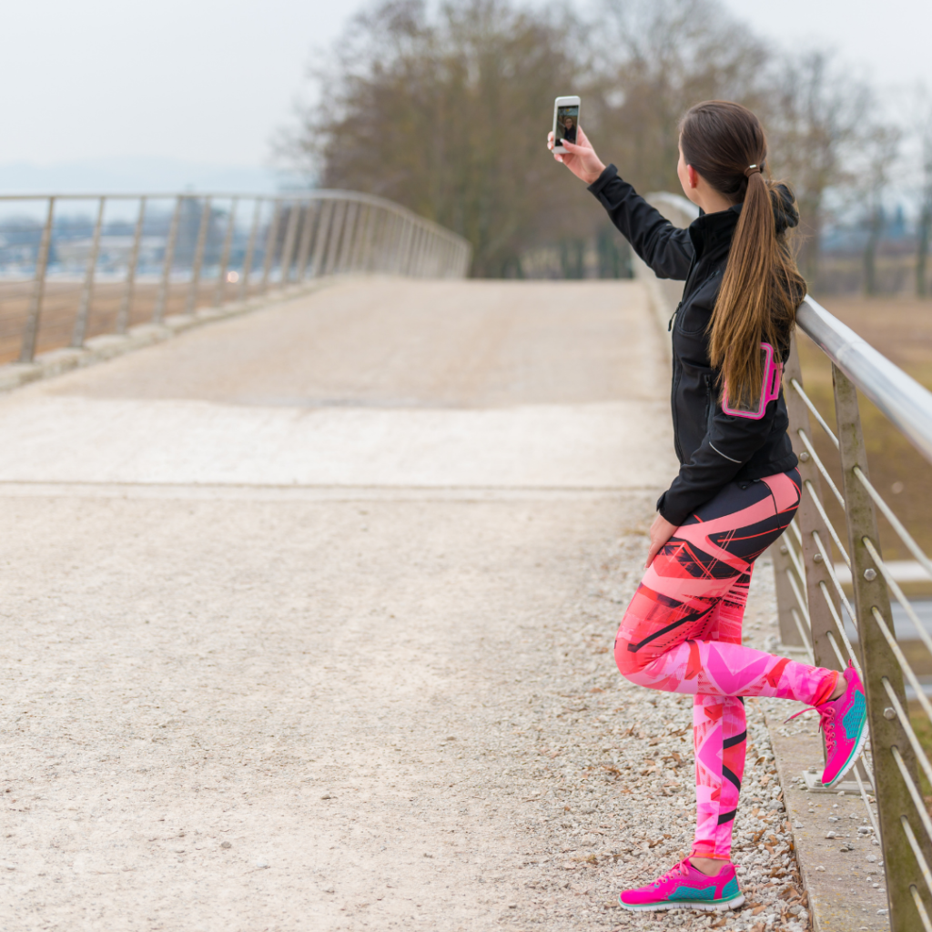 woman in exercise clothing on bridge using mobile device for storytelling