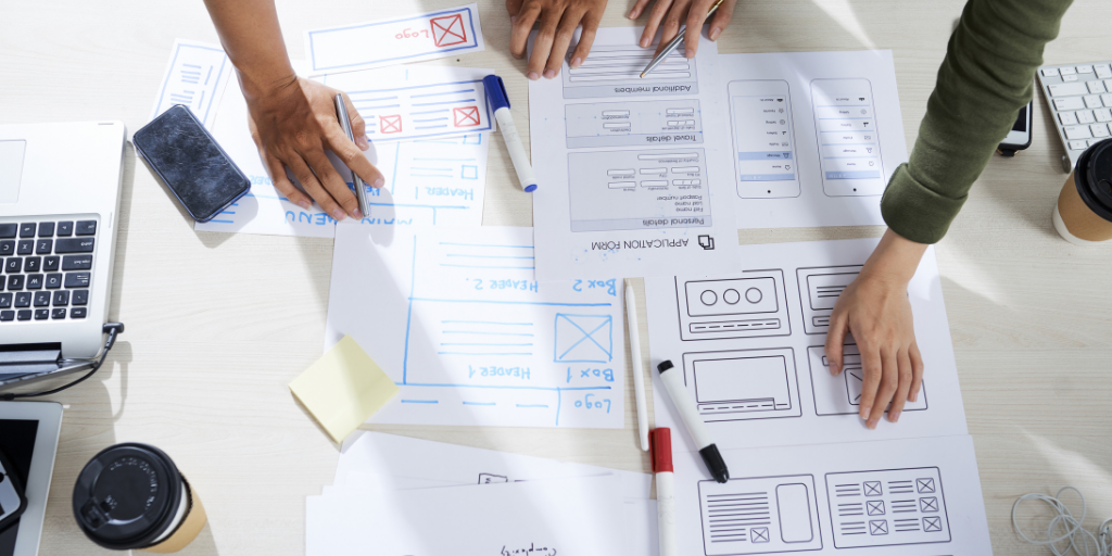 Two team members leaning over desk covered in documents brainstorming about UX design