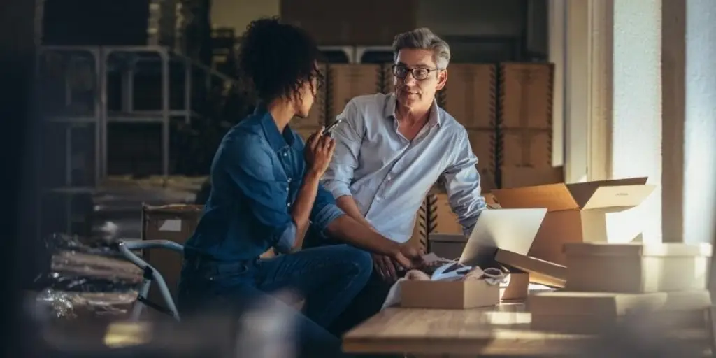 Two business owners in their warehouse discussing their online business plans.