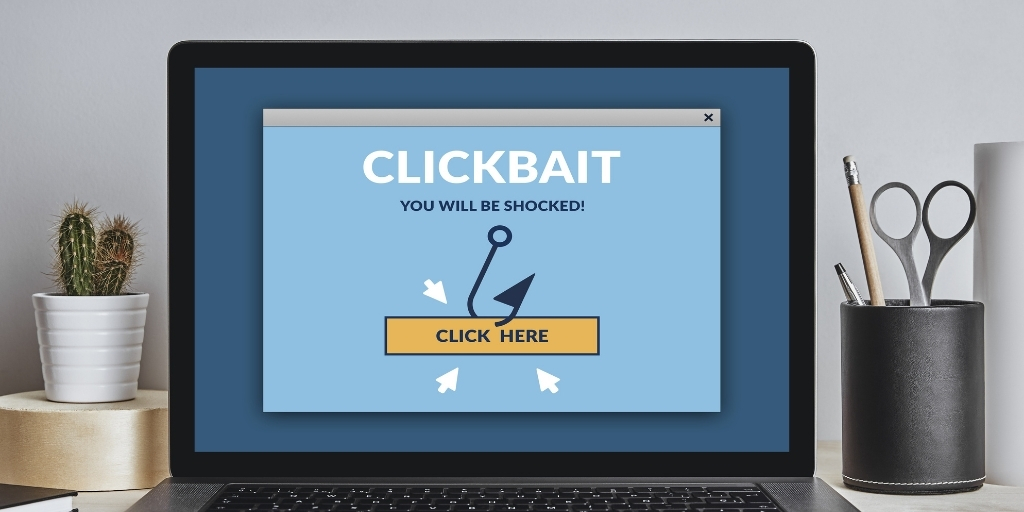 A laptop screen displays the words “clickbait you will be shocked” and a fishing hook next to the words “click here.”