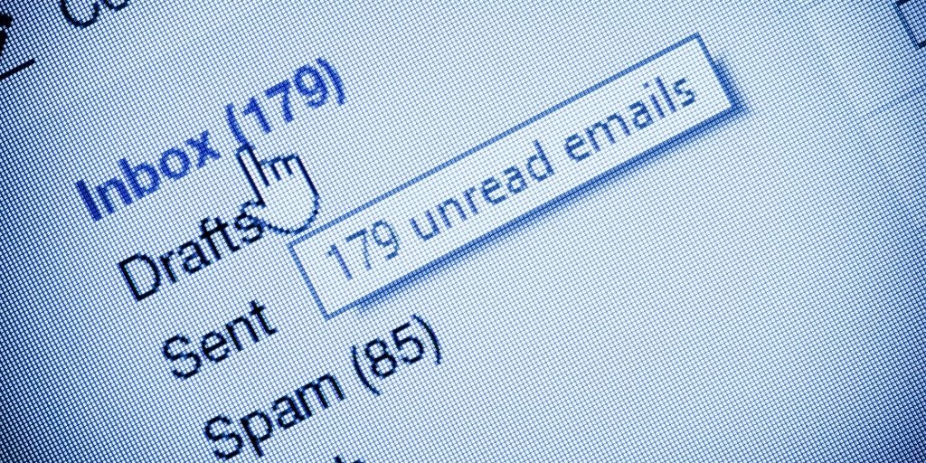 A computer screen shows email folders, including an inbox with dozens of unread messages and emails in the spam folder.