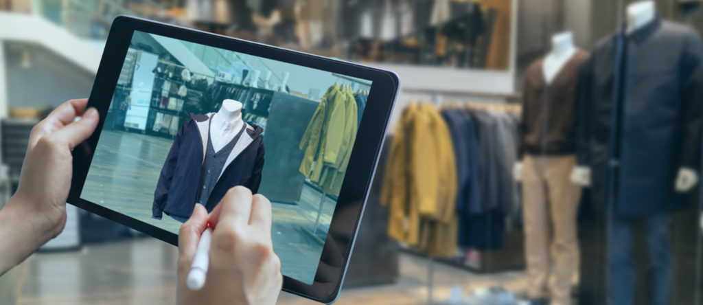 Person standing in front of clothing store holding tablet with 3D fashion design program to show human and AI collaboration.