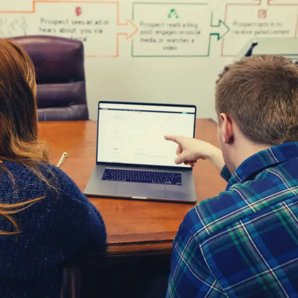 two people looking at data on a laptop.