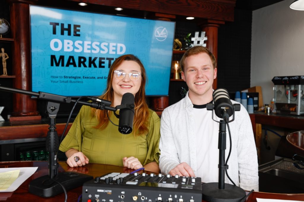Andrew and Holland from Viral Solutions smiling in front of Obsessed Marketer podcast background.