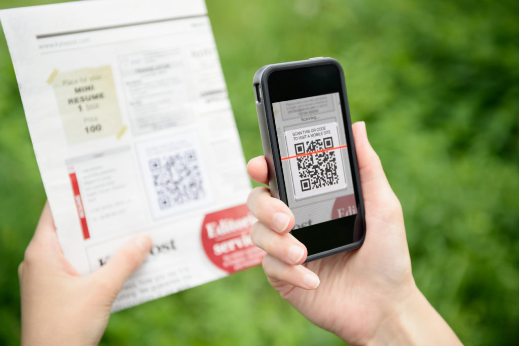 QR code marketing - Woman using a smartphone to scan a QR code to view a restaurant menu.