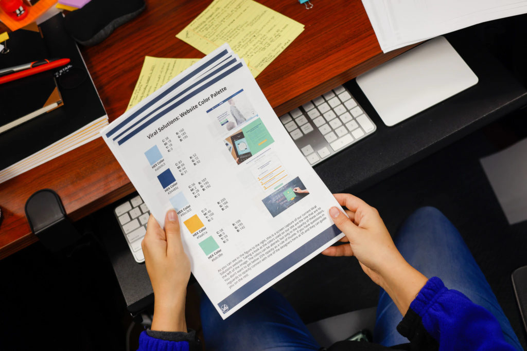 Viral Solutions’ team member holding a sheet of paper with website color palette.