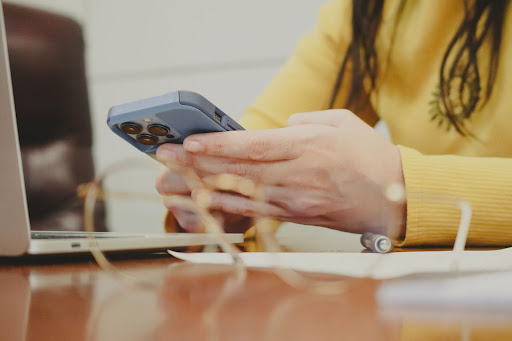 Woman using a smartphone to track marketing campaigns using UTM parameters.