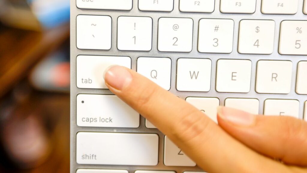 Finger pointing to tab button on keyboard as concept for making website usable via keyboard.