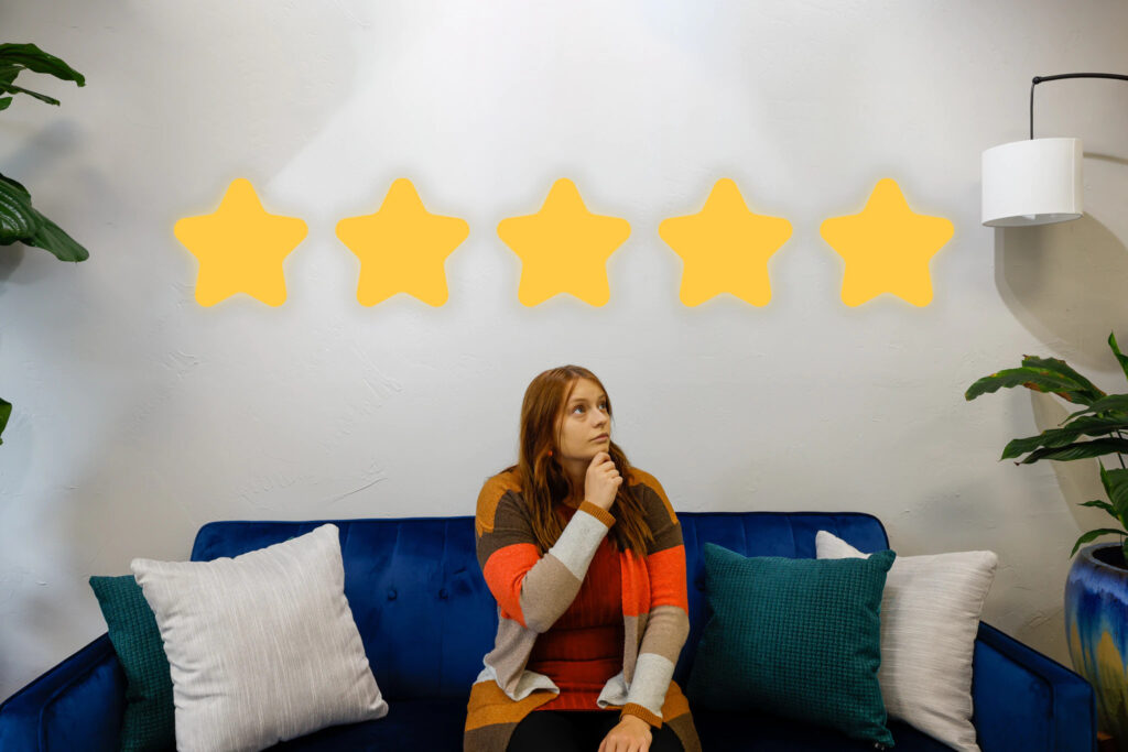 Taylor from Viral Solutions sitting on blue couch looking pensive with five gold star overlay.