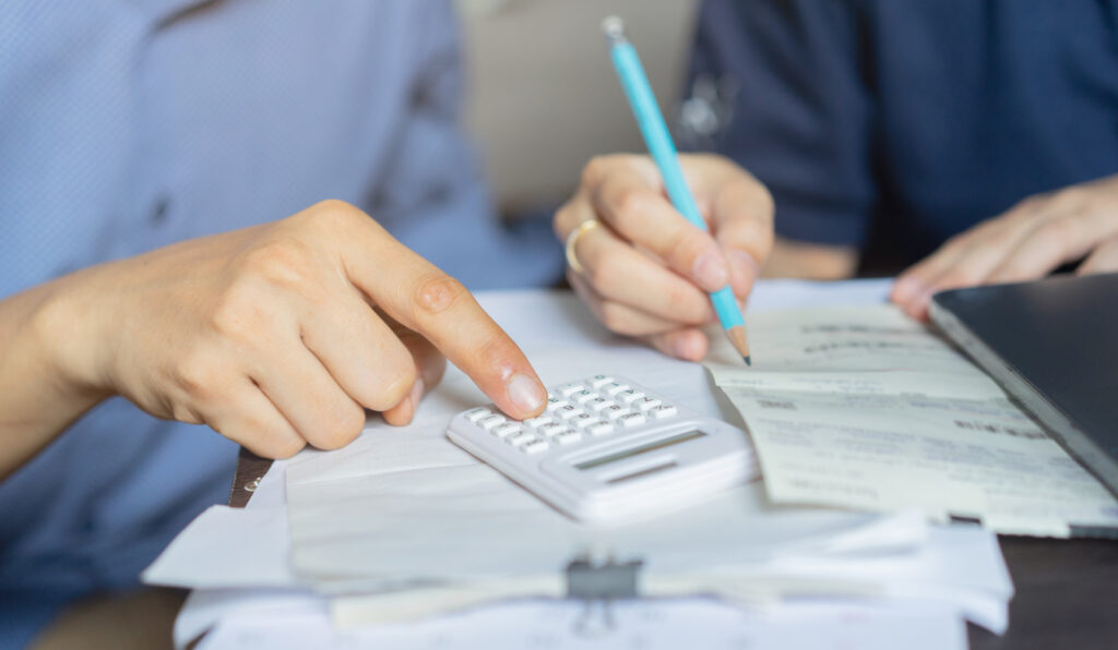 Two business owners reviewing finances while using a calculator as a concept of preparing for a recession.