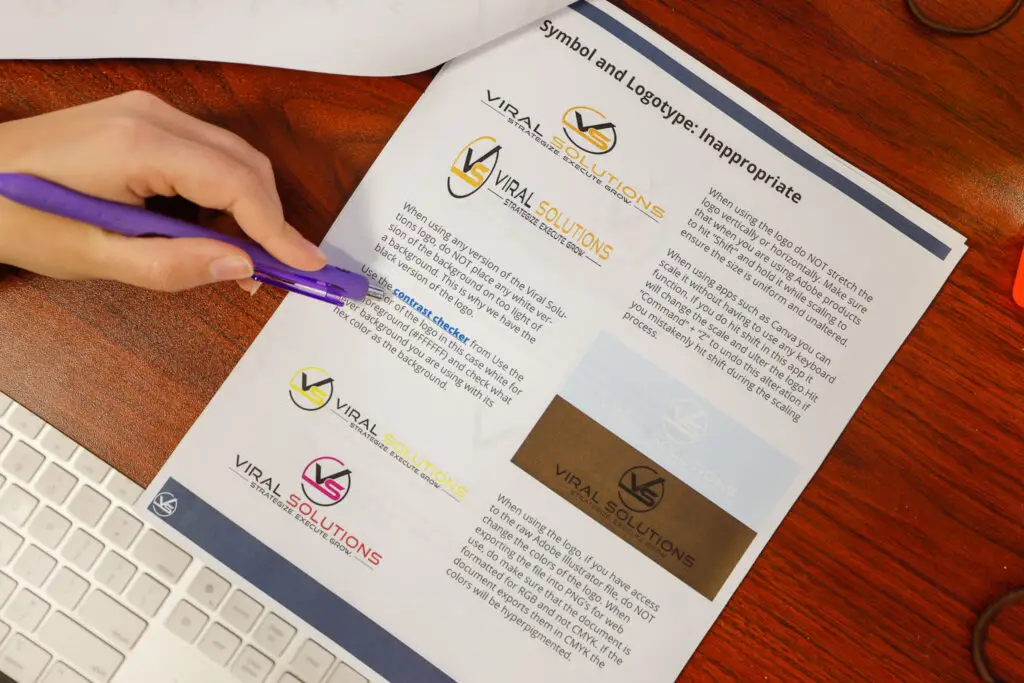 Designer using a purple pen to point at a paragraph on a logo use requirement page.